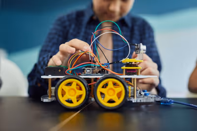 Engineering student assembling robotic chassis with jumper wires