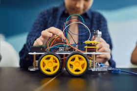 Engineering student assembling robotic chassis with jumper wires